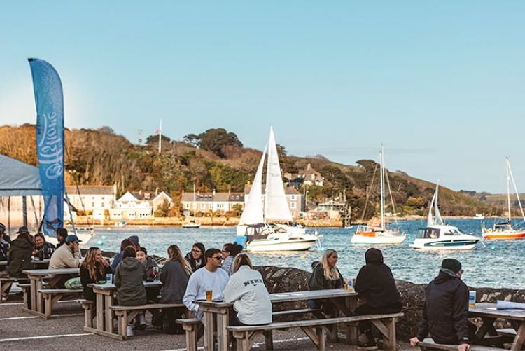 Menschen sitzen und beobachten den Hafen von Falmouth im Pub-Garten von The Working Boat